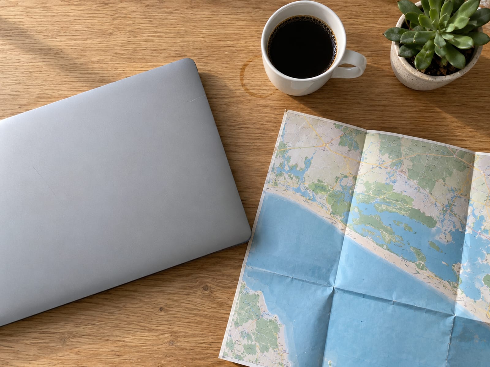 An insurance agent's desk with a laptop, a printed map and a coffee cup, seen from above