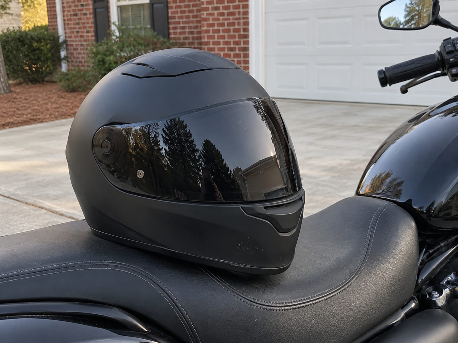 Un casco integral para motocicleta apoyado en el asiento de una moto estacionada en una entrada