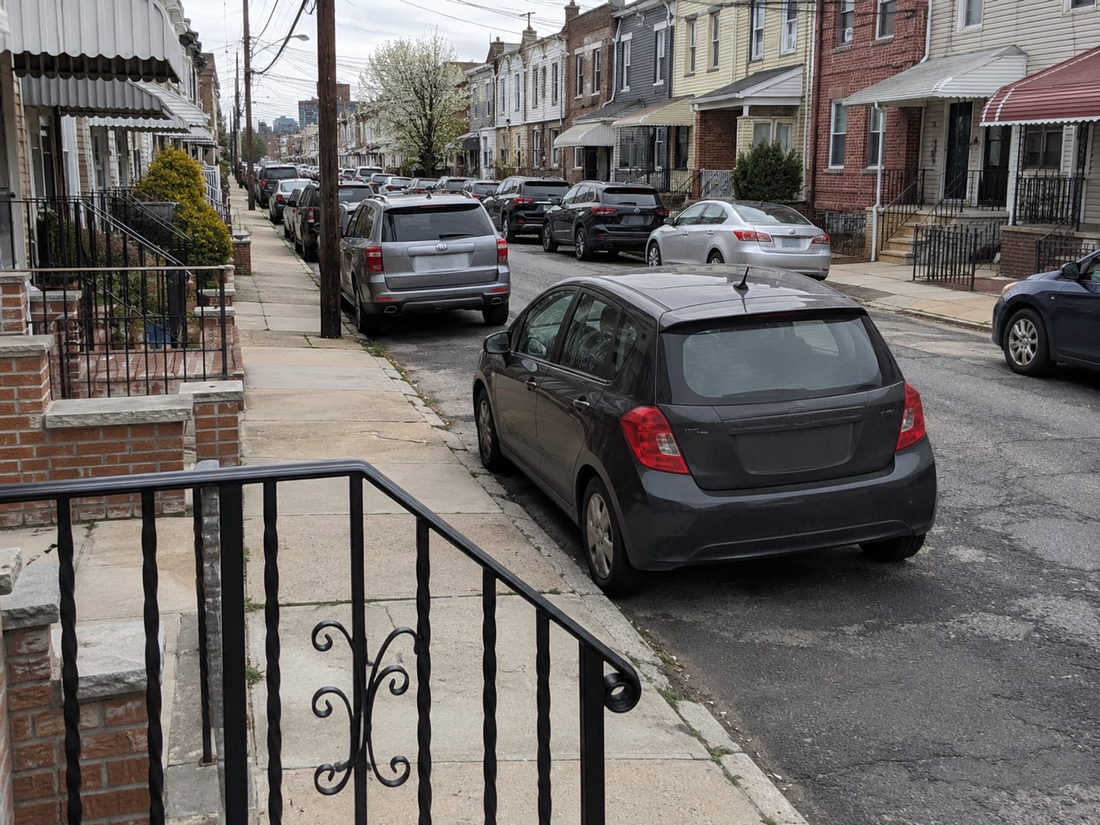 A compact car parked on a dense residential street of attached homes in a North Jersey town