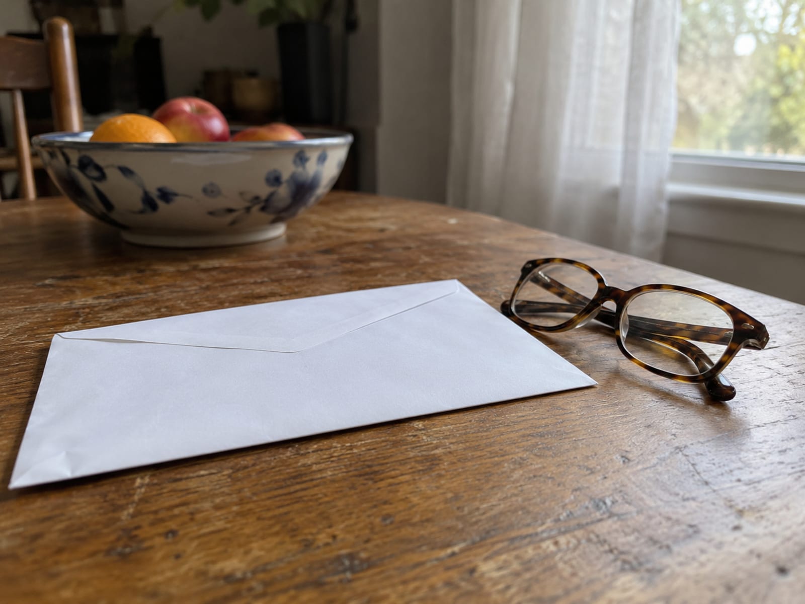 Un sobre sin abrir y un par de lentes para leer sobre una mesa de cocina