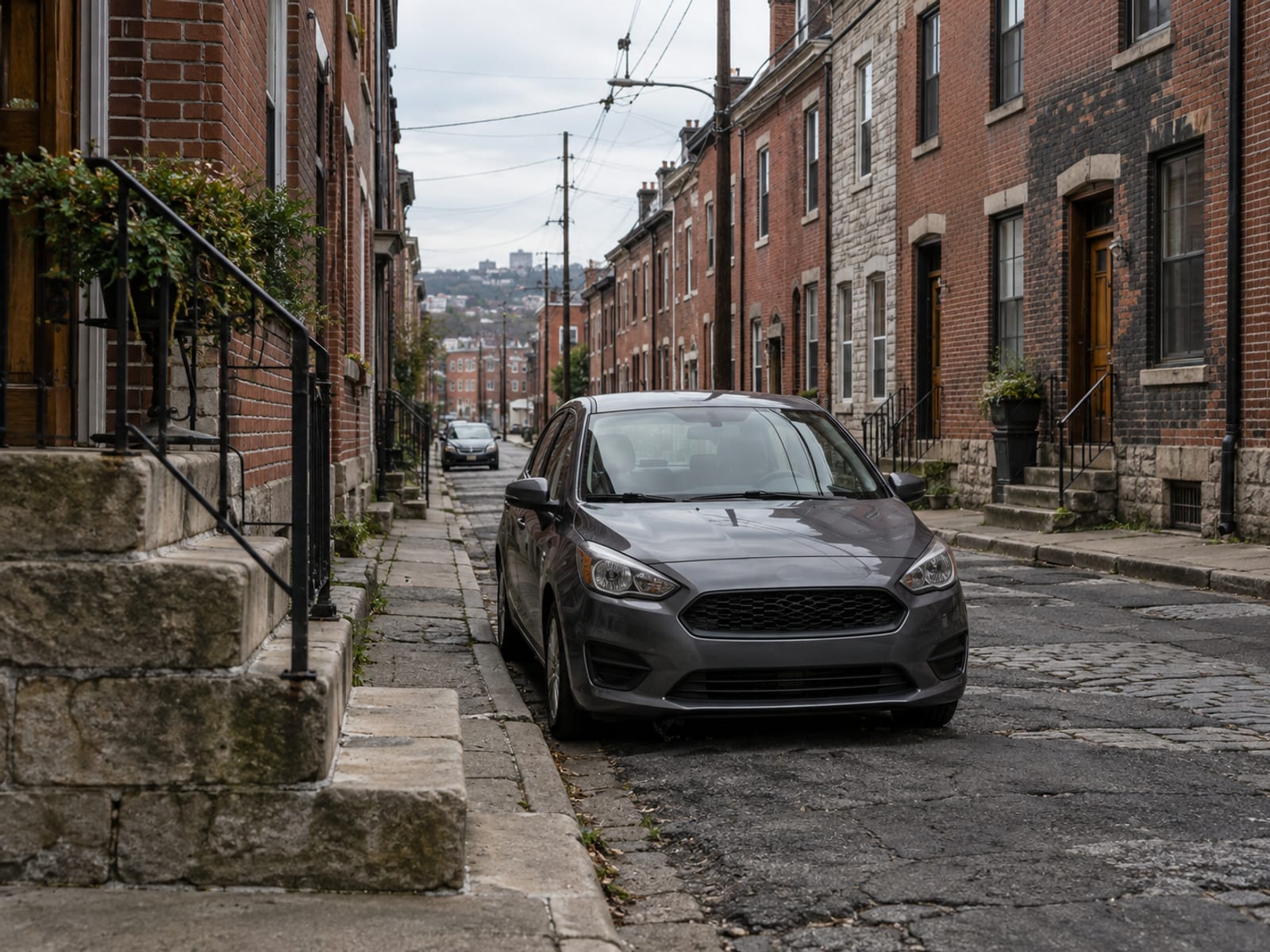 A compact car parked on a narrow Pennsylvania city street lined with brick row houses
