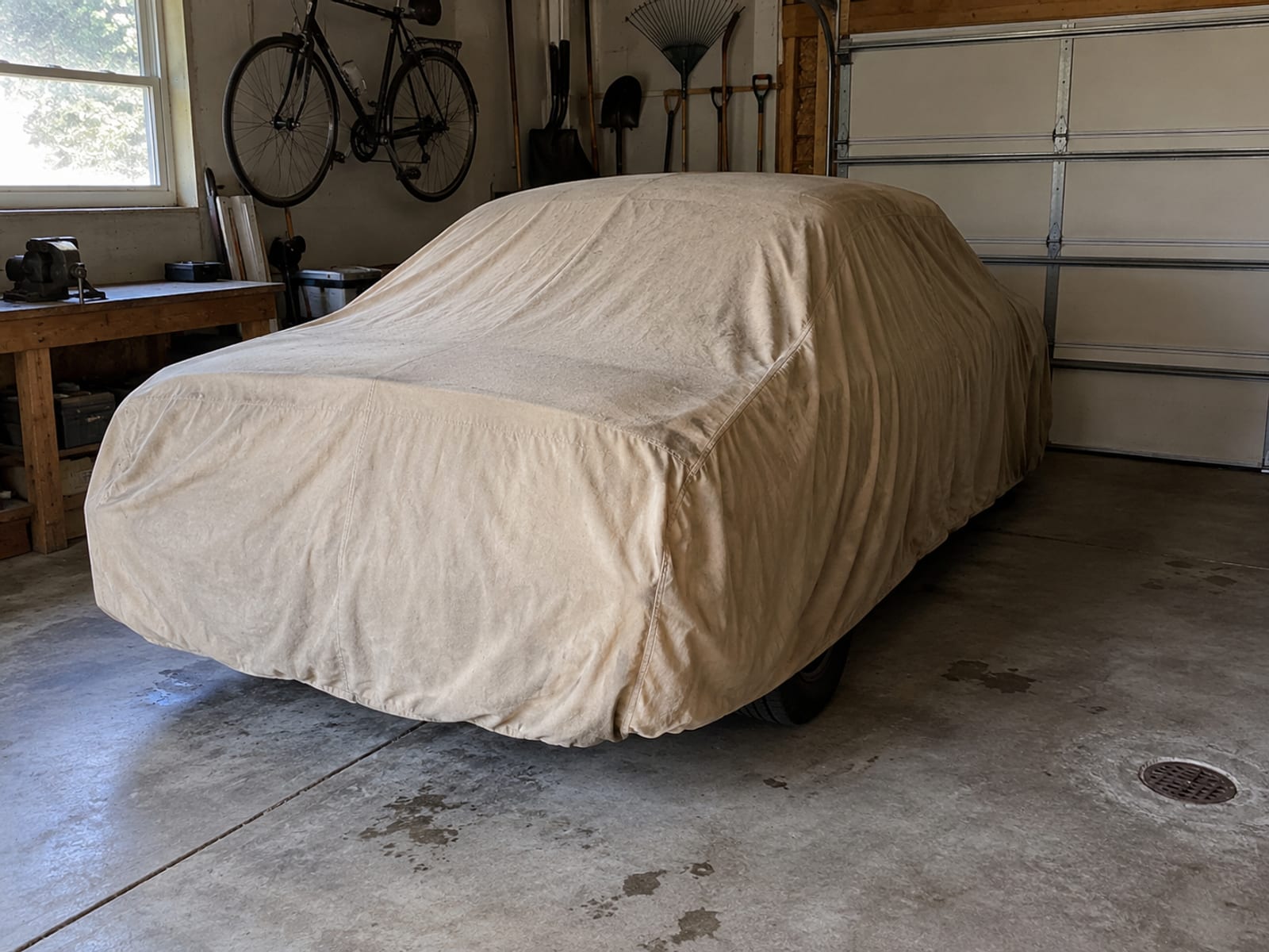 A car under a fitted cloth cover in a home garage