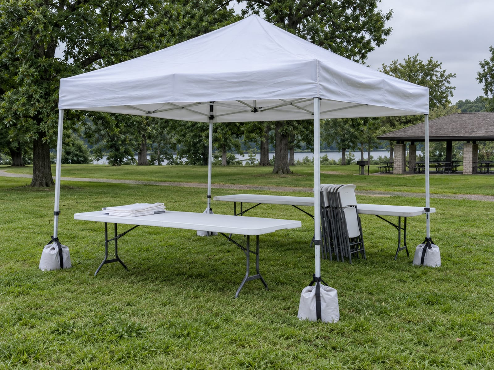 Mesas plegables y una carpa de toldo montadas sobre un césped vacío antes de un evento al aire libre