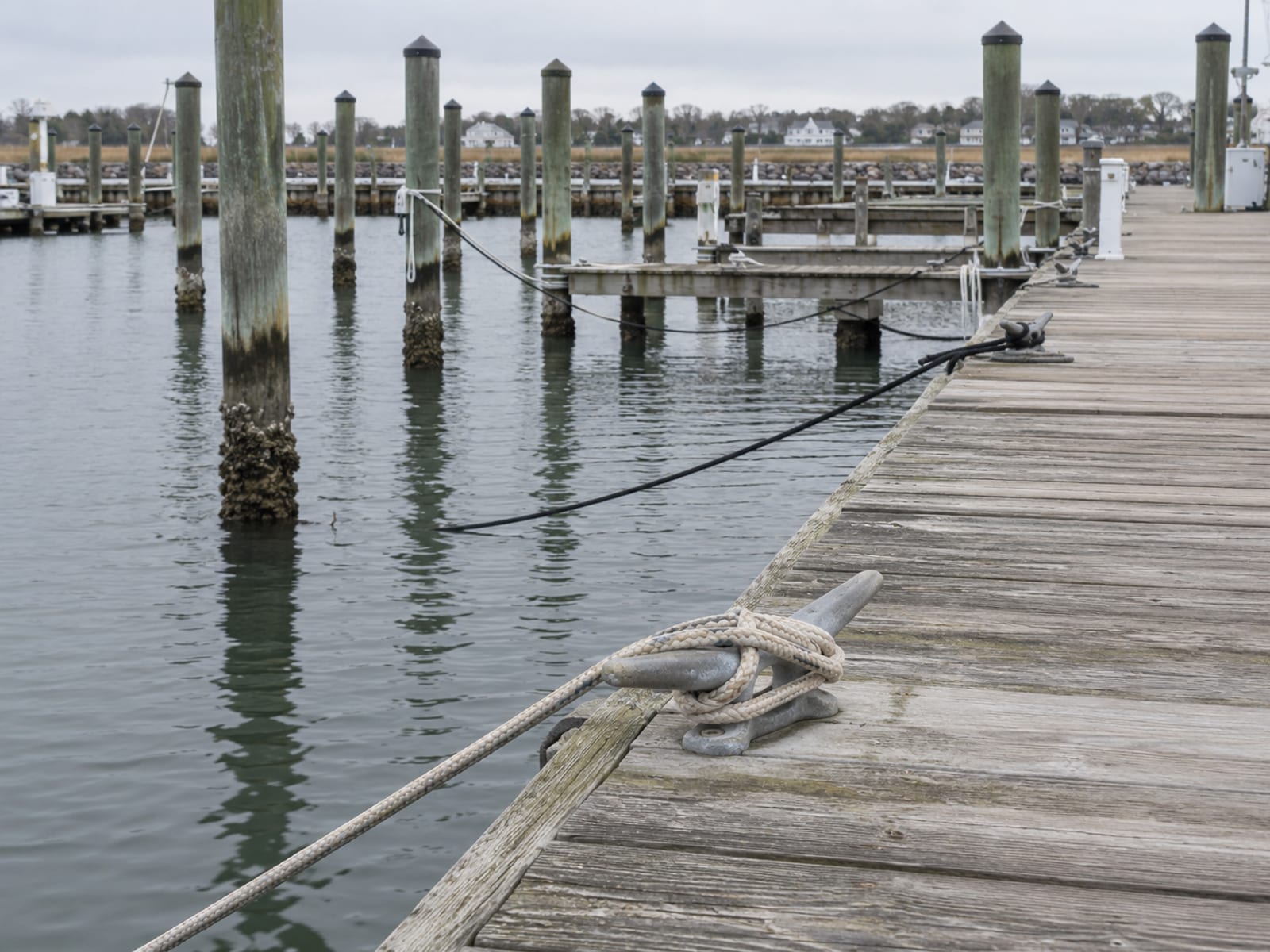 A row of empty boat slips along a wooden marina dock with lines and cleats on calm water
