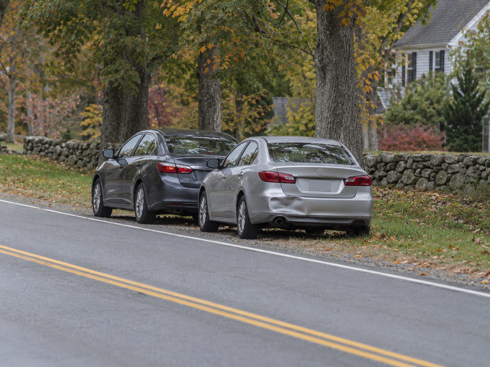 Two cars stopped at the side of a suburban road after a minor fender bender, seen from a distance