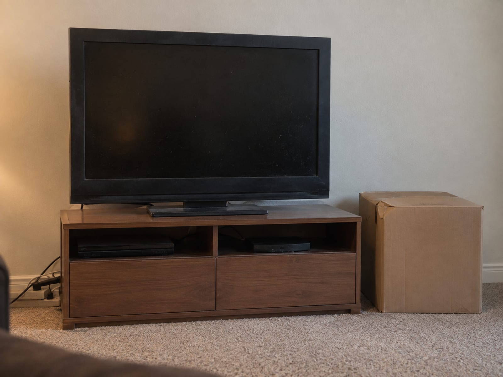 An older television on a stand beside a cardboard box in an apartment