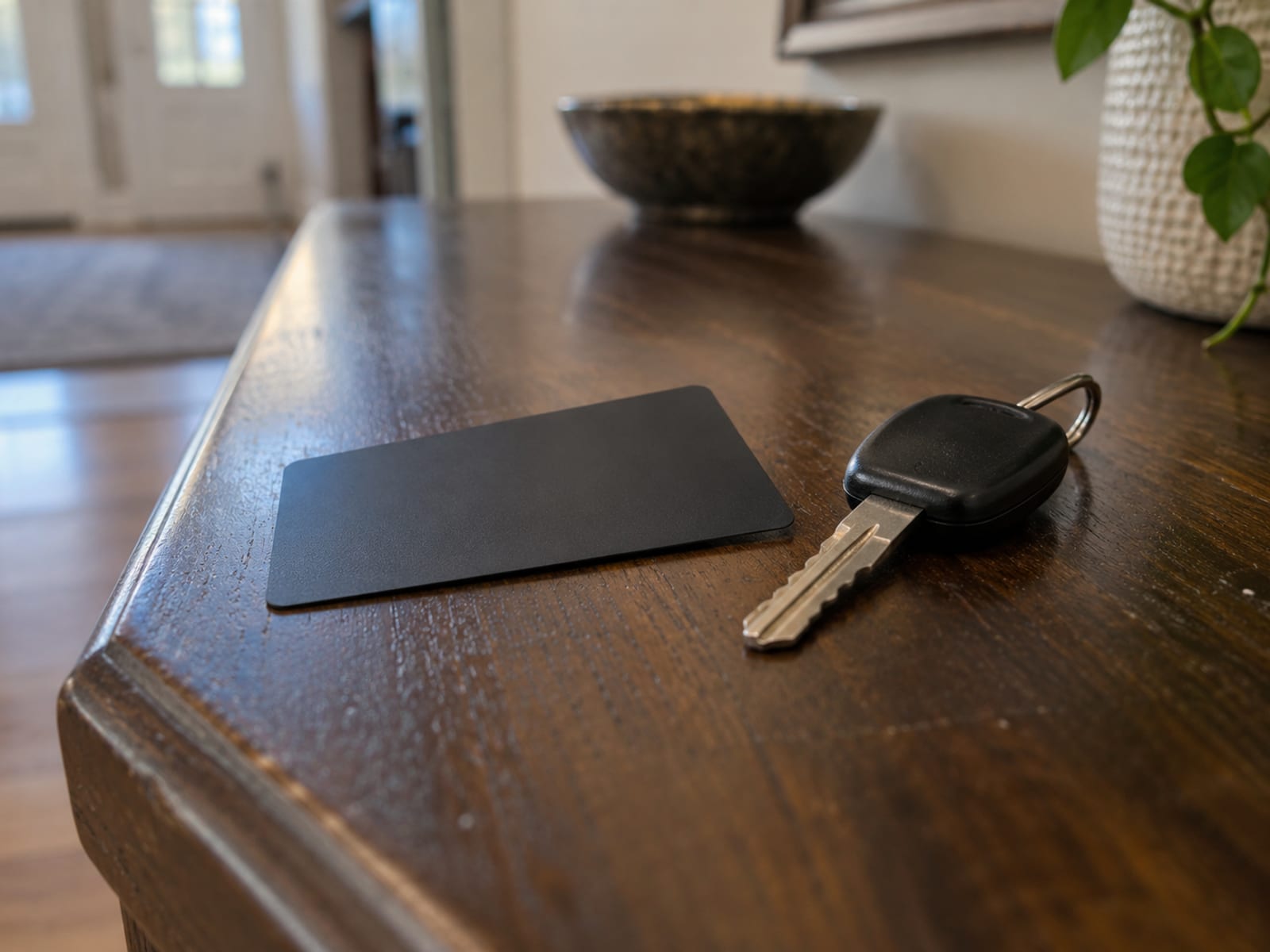Una tarjeta de pago lisa y sin marca junto a una llave de auto sobre una mesa de madera oscura