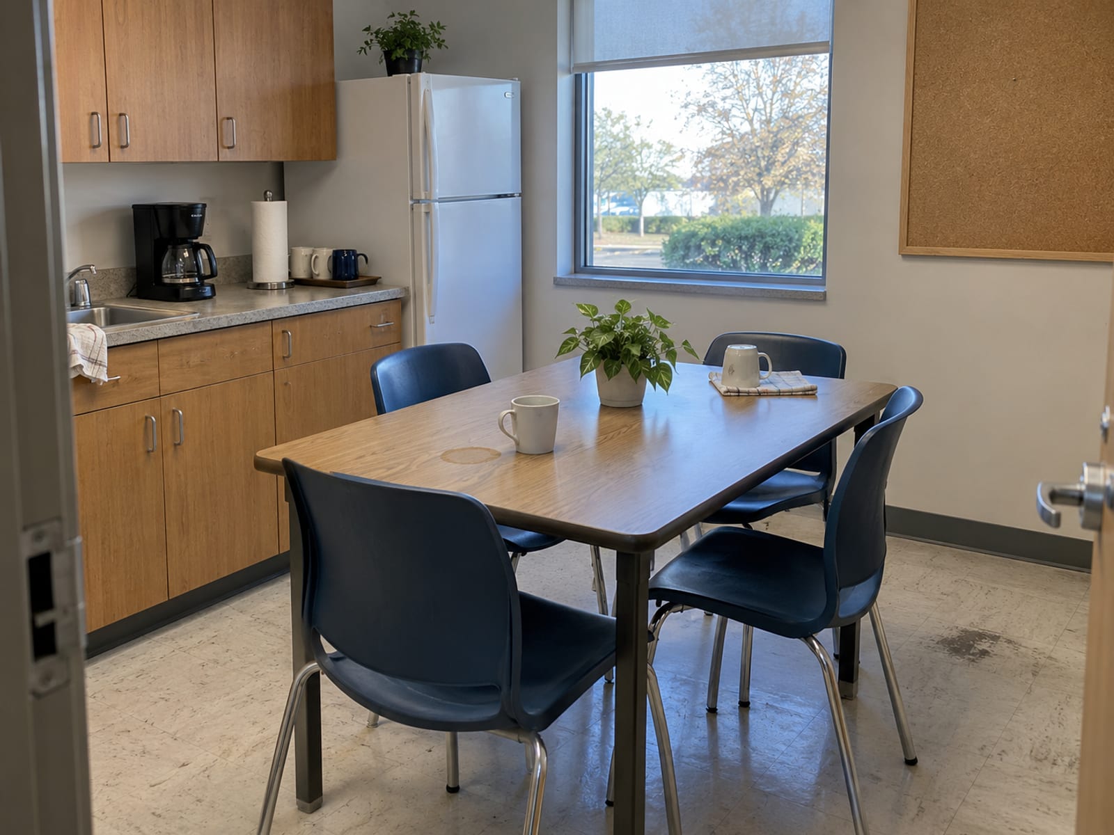 An empty small-business break room with a table, chairs and a coffee maker in morning light