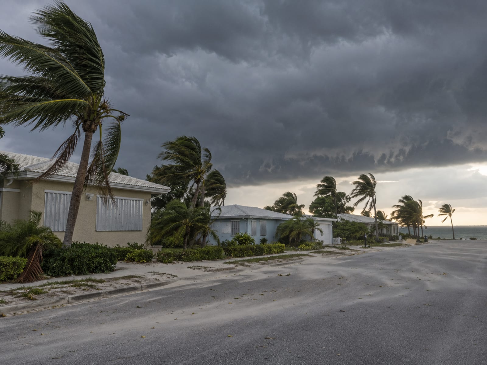 Storm clouds gathering over a row of coastal homes and palm trees