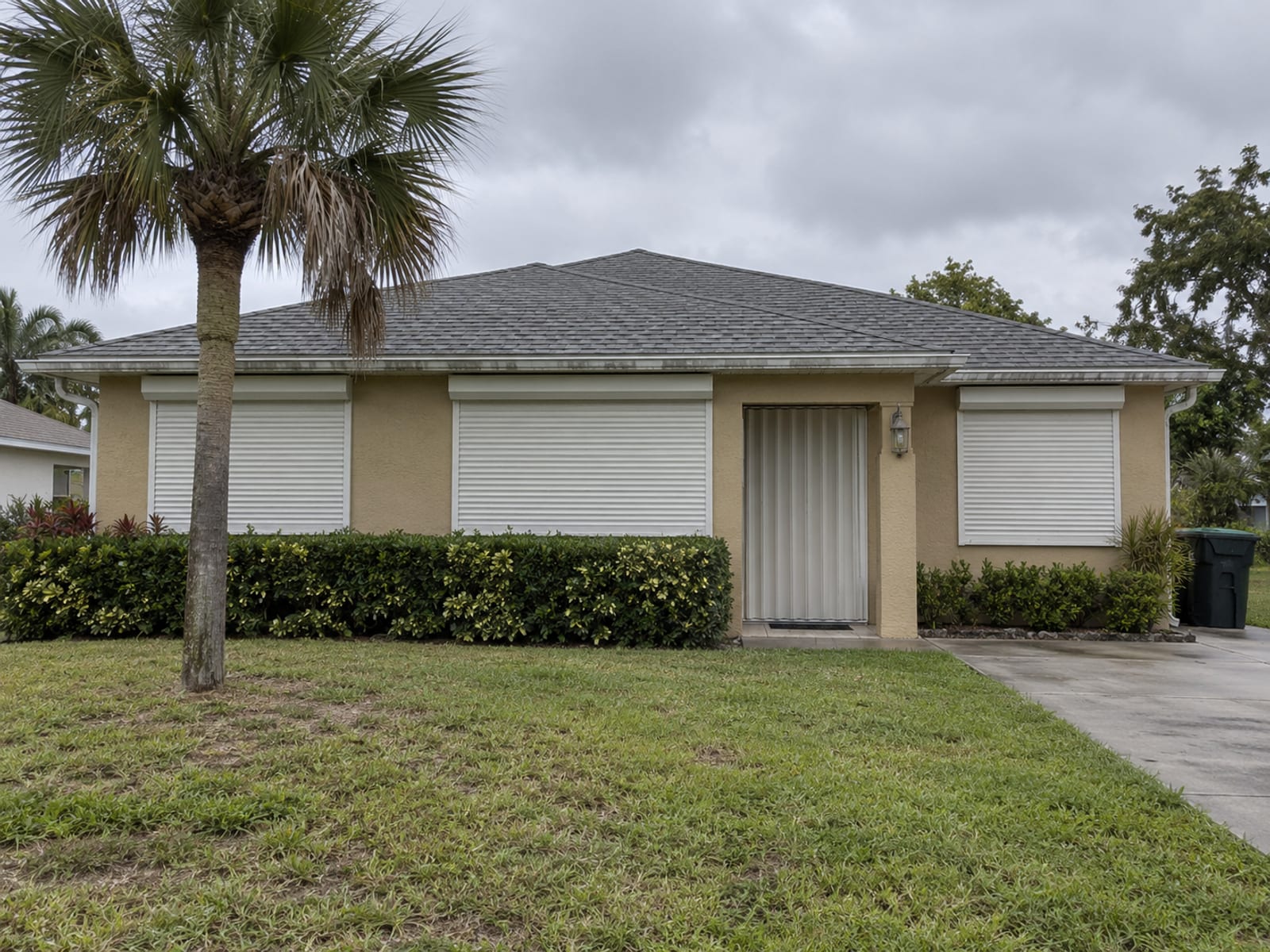 Una casa de un piso en Florida con contraventanas de tormenta cerradas bajo un cielo gris
