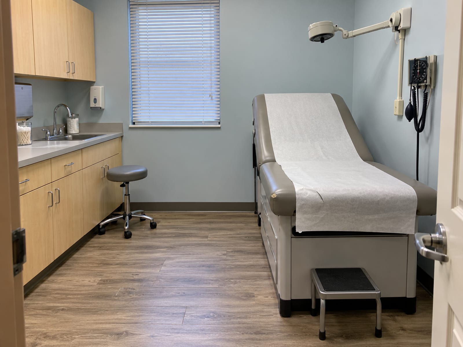 An empty, brightly lit urgent care exam room with a padded table