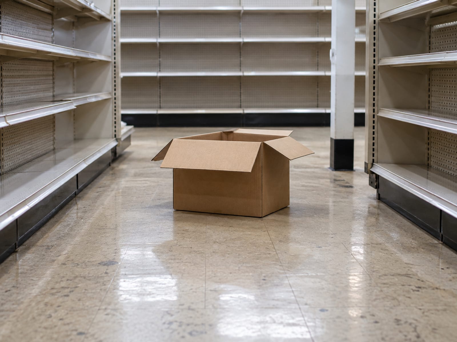 A customer stepping around a cardboard box on the floor of a small shop