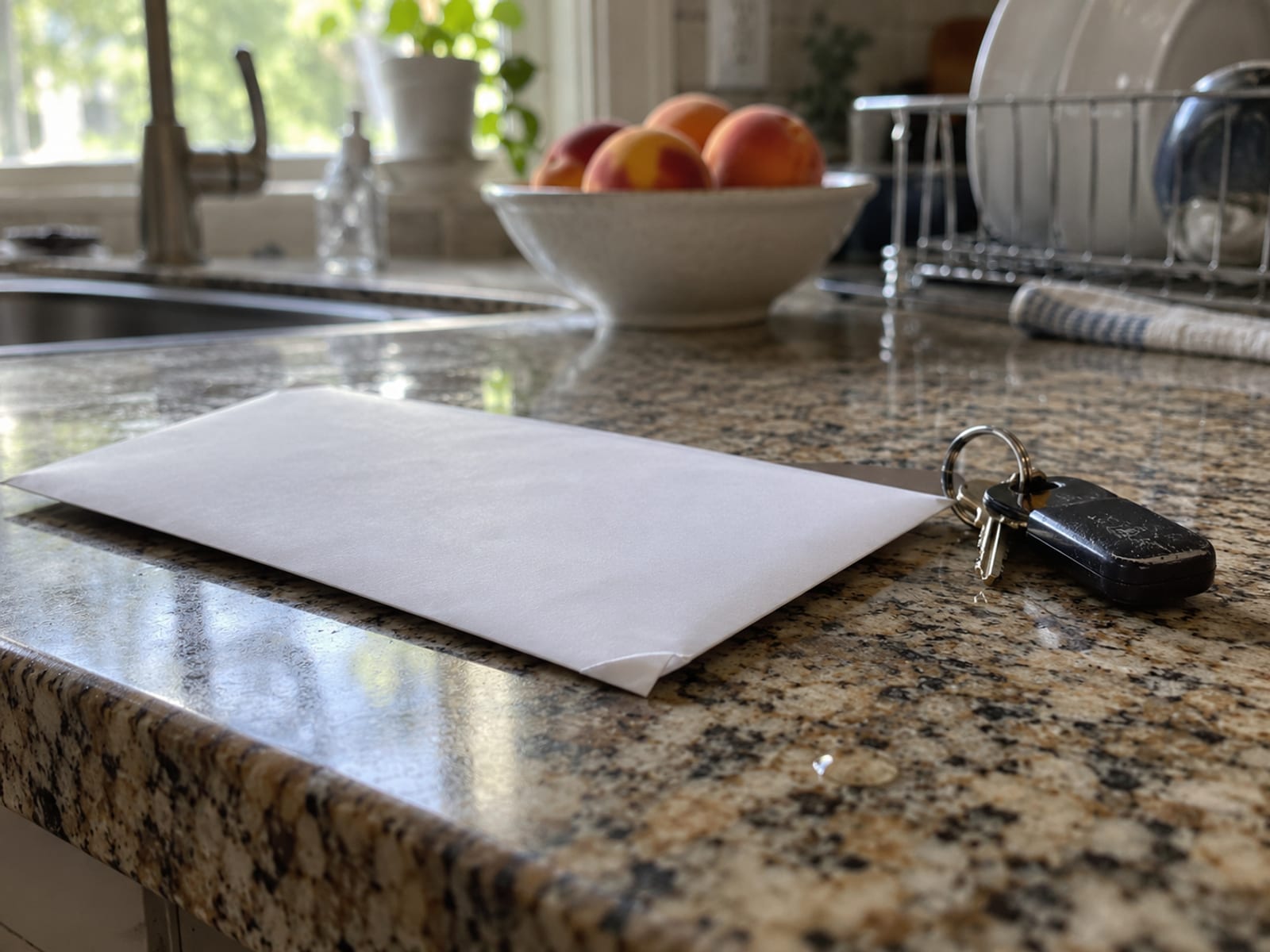 An unopened envelope resting on a kitchen counter beside a set of car keys