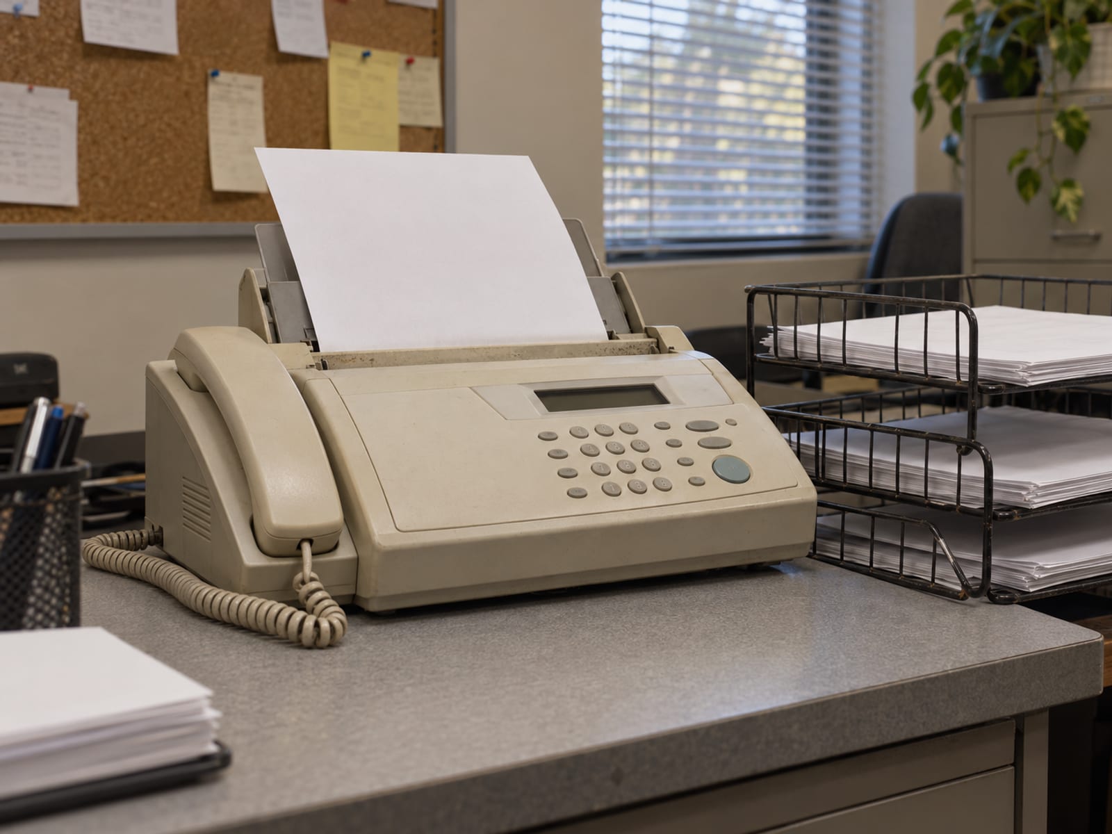 An office fax machine with a sheet of paper feeding through, the page blank side up