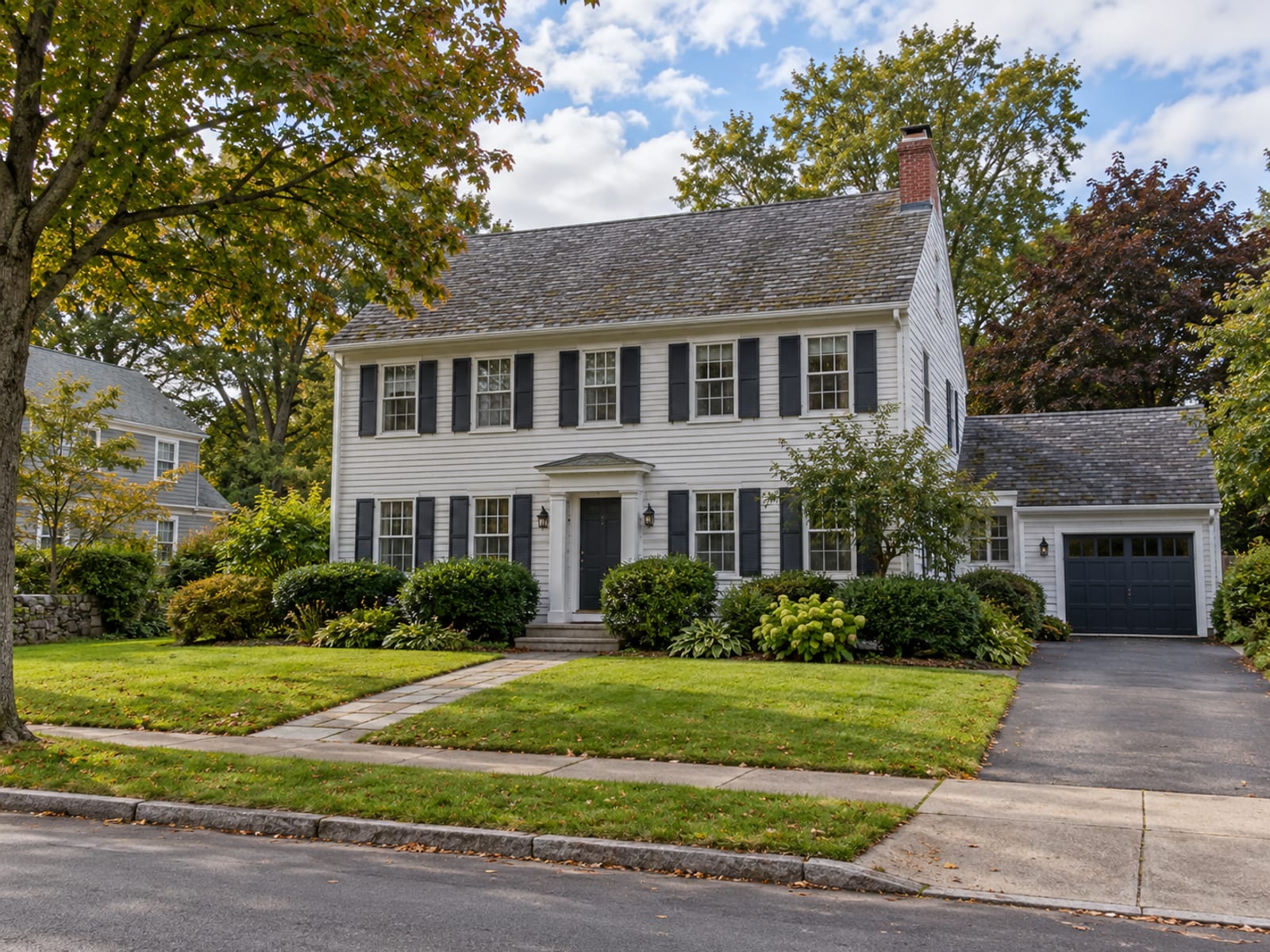 A modest suburban house with a tidy lawn under a partly cloudy sky