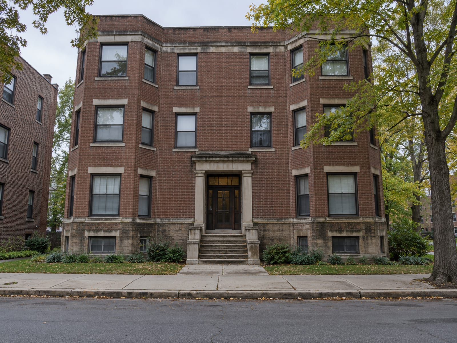 An apartment building exterior with a row of windows and a shared front entrance
