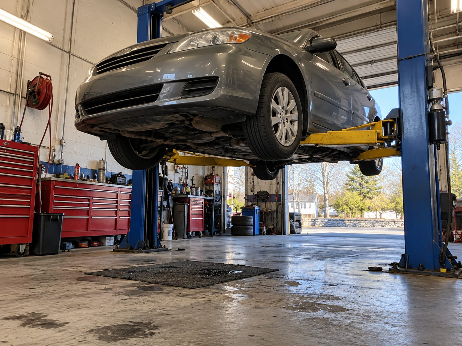 An empty auto repair bay with a car on a lift and tools on the wall, no signage