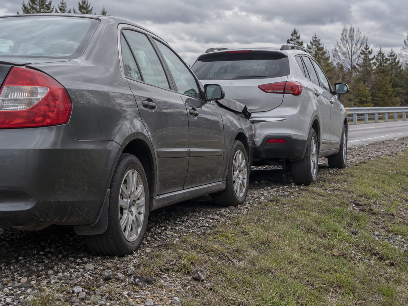 Two cars pulled over on a highway shoulder after a rear-end collision