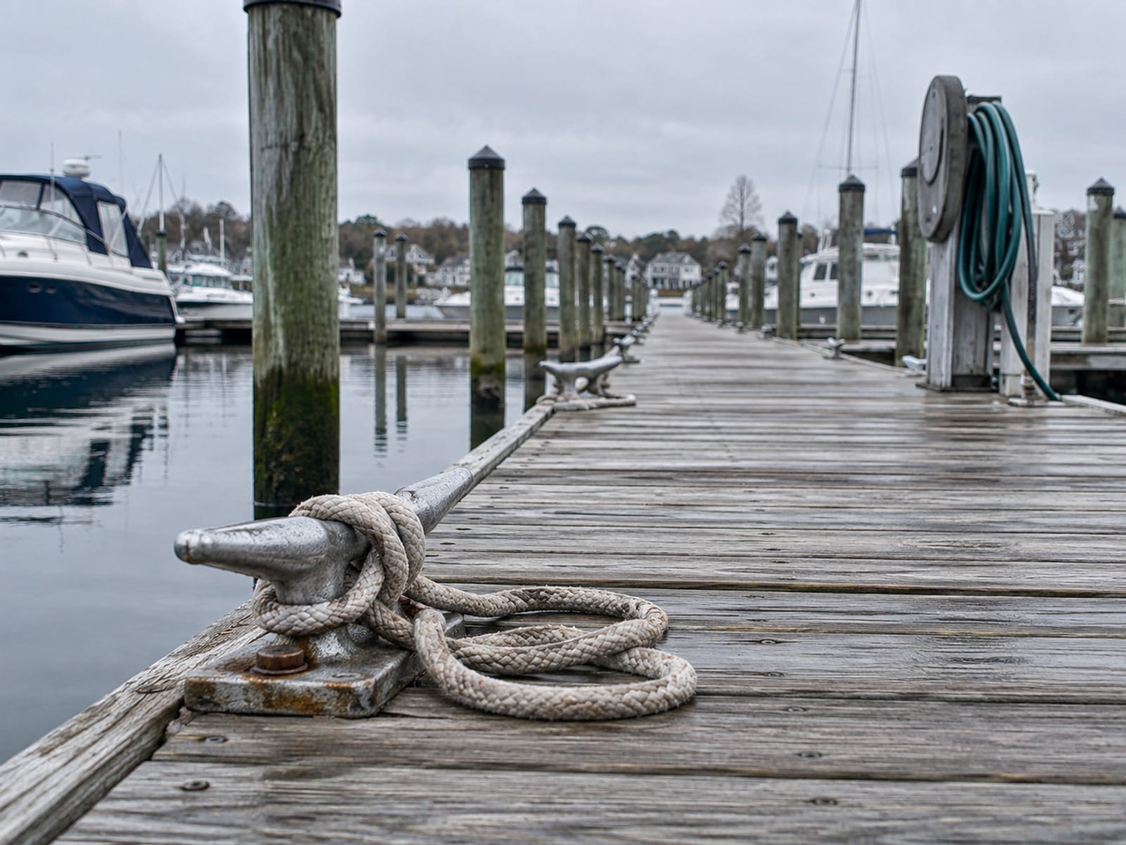 A row of empty marina slips with dock lines and cleats along a wooden pier