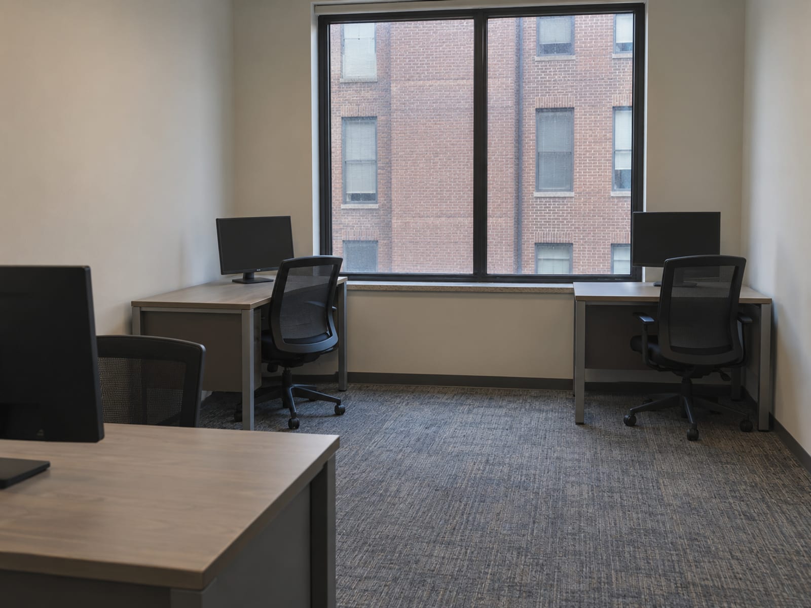 An empty small-business office with desks, chairs and a window onto a city street