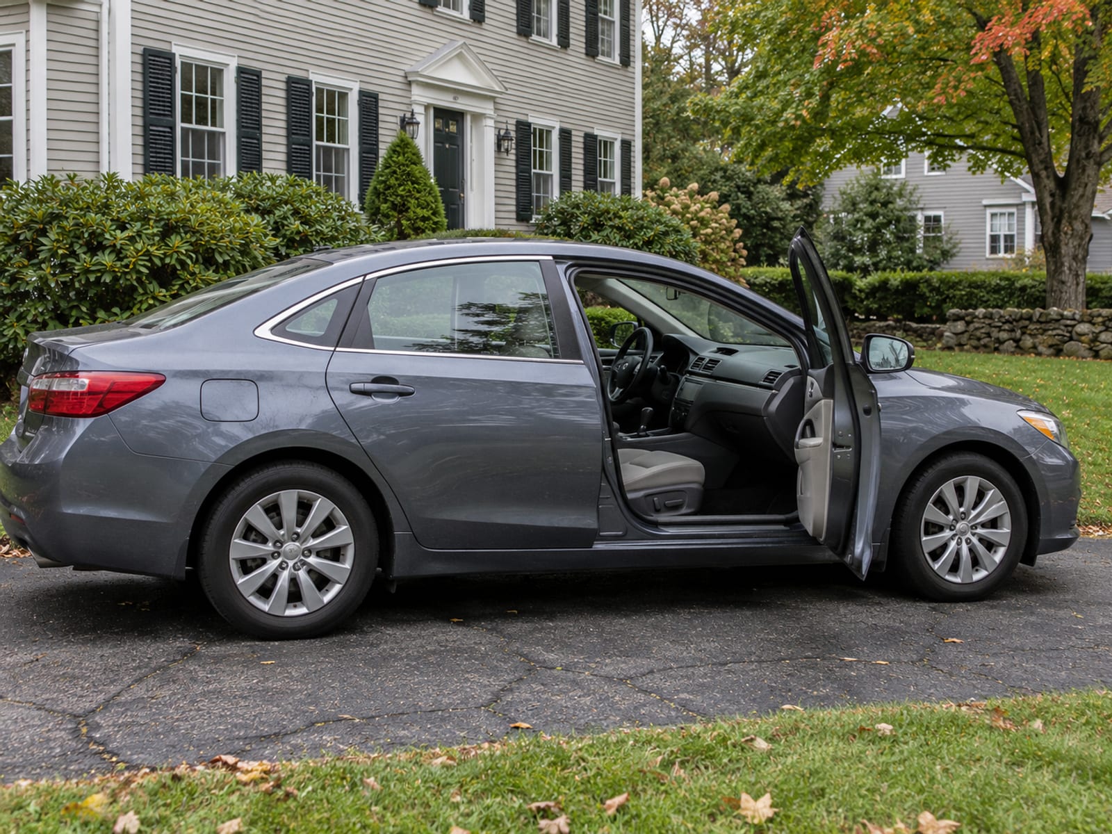 A family sedan parked in a residential driveway with its passenger door open, seen from the side with no people or plates visible