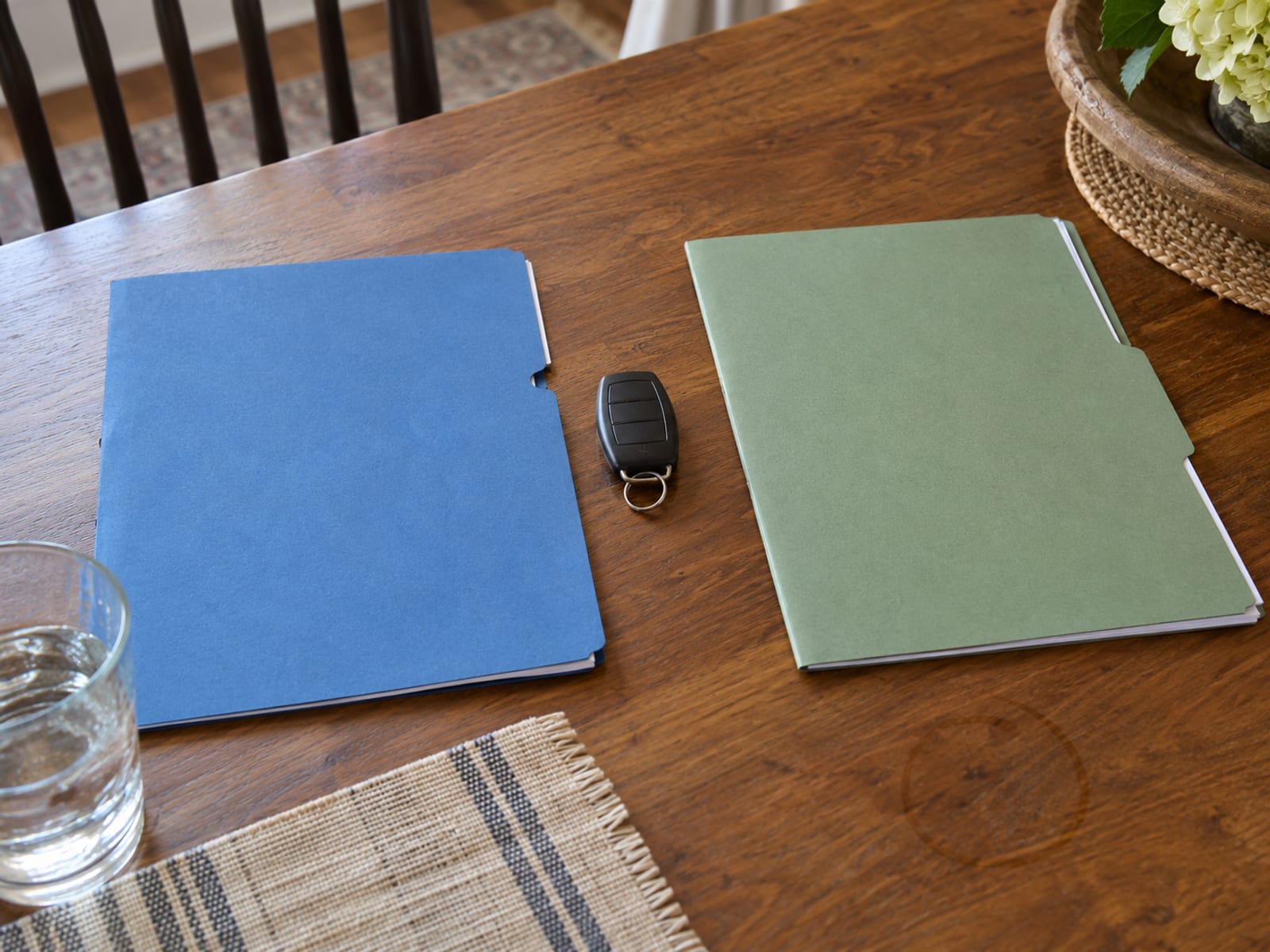 Two blank policy folders side by side on a desk with a car key and a pen between them