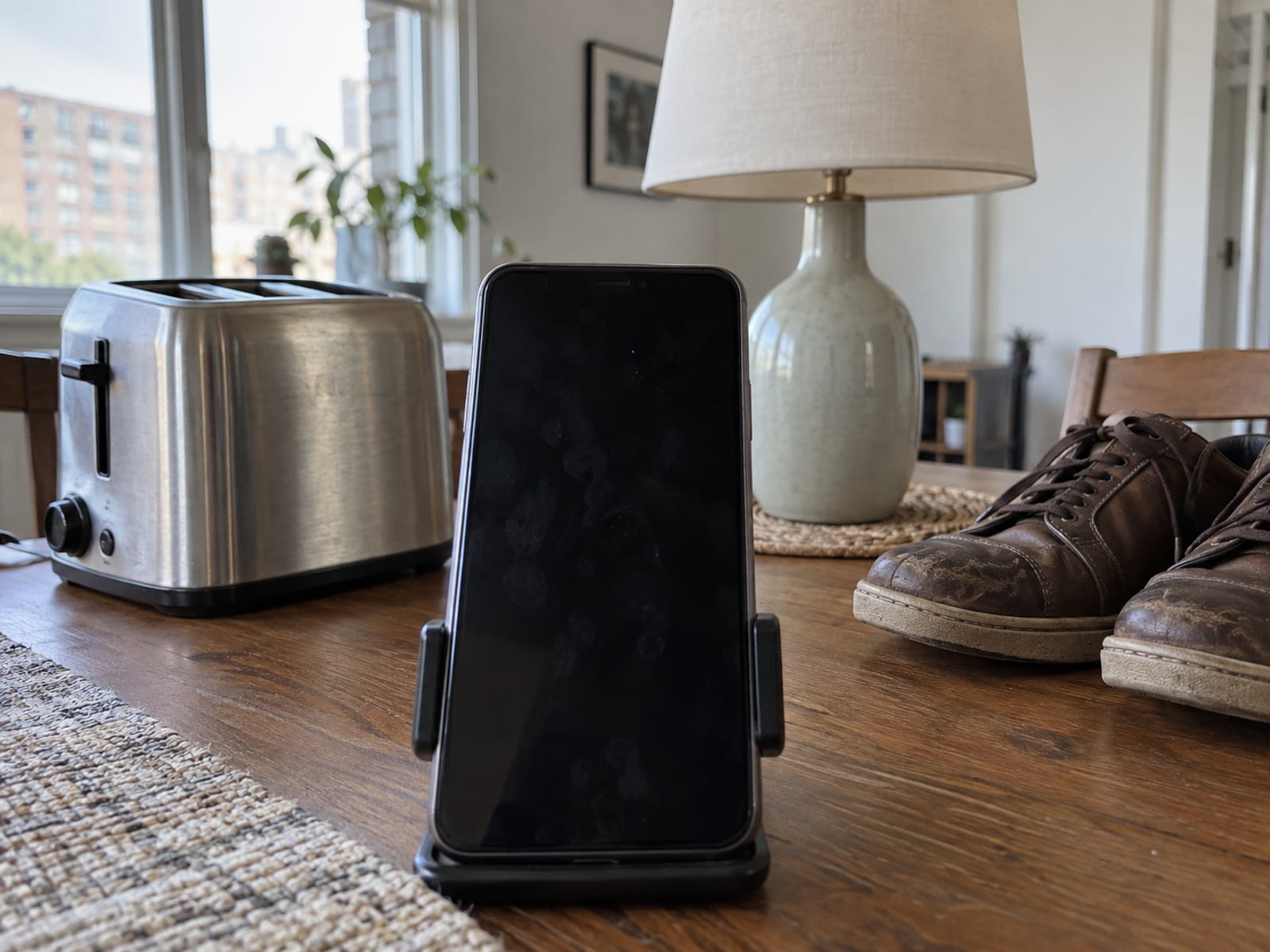 A smartphone on a table photographing a row of household items laid out for an inventory