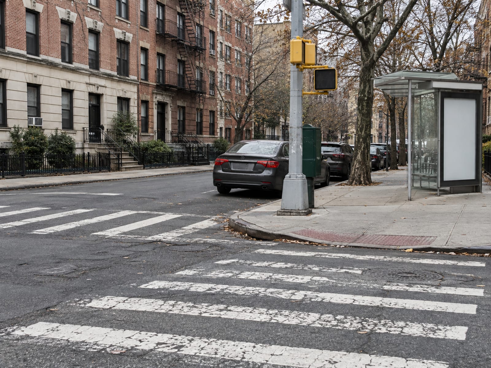 Una esquina tranquila de la ciudad con un cruce peatonal, un carro estacionado y una parada de autobús a la luz del día