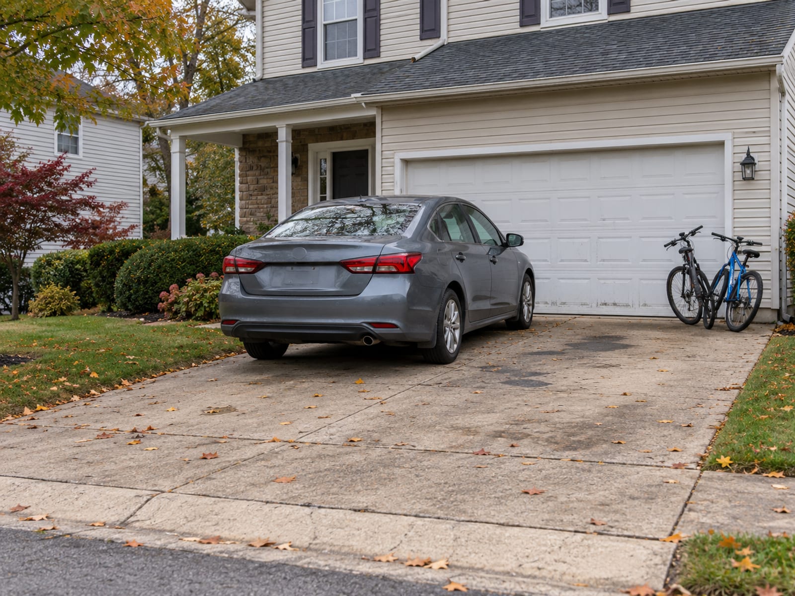 A family car parked in the driveway of a Pennsylvania split-level home with bicycles by the garage