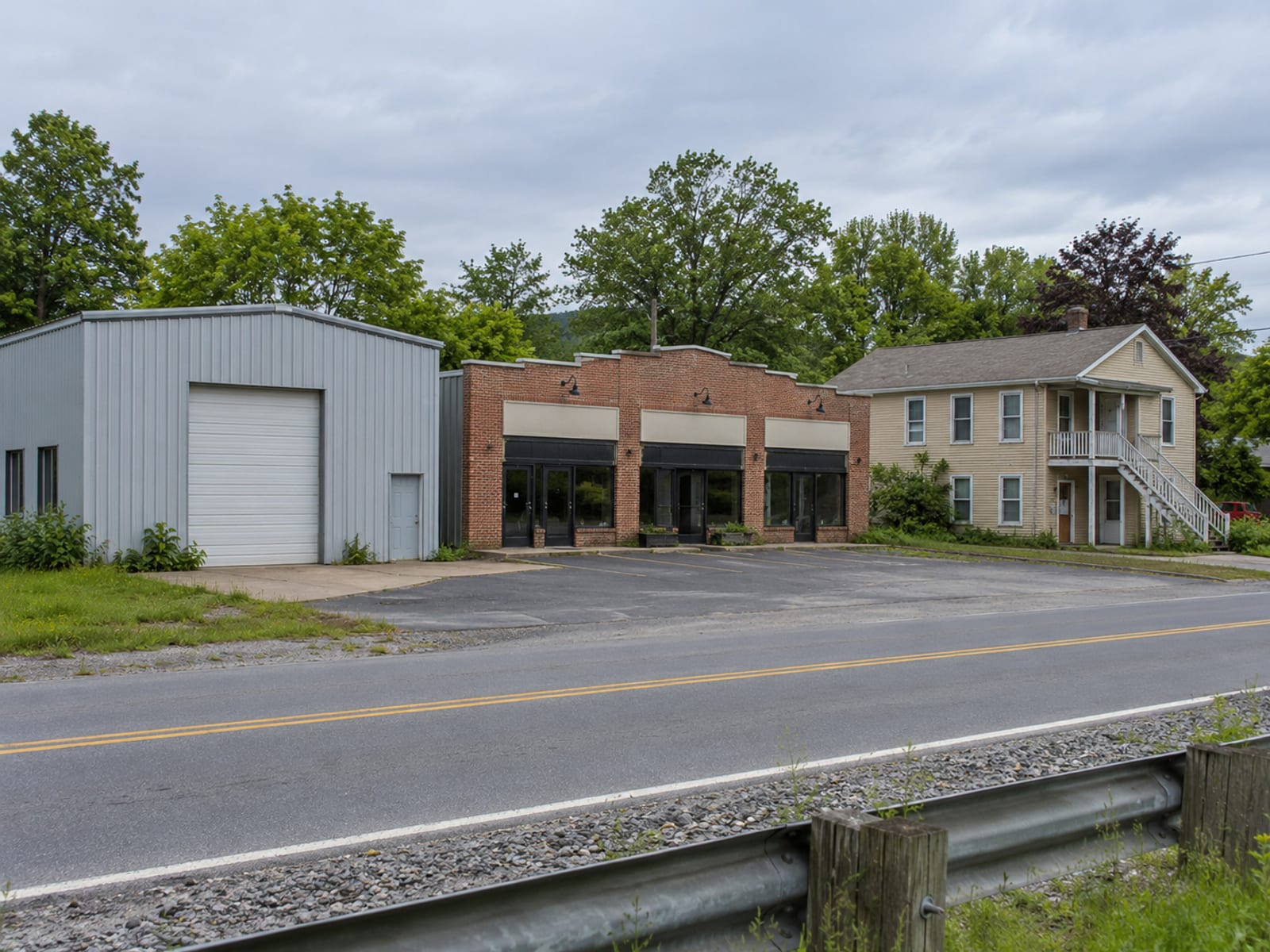 A row of different commercial properties side by side: a warehouse, a small retail center and a low apartment building