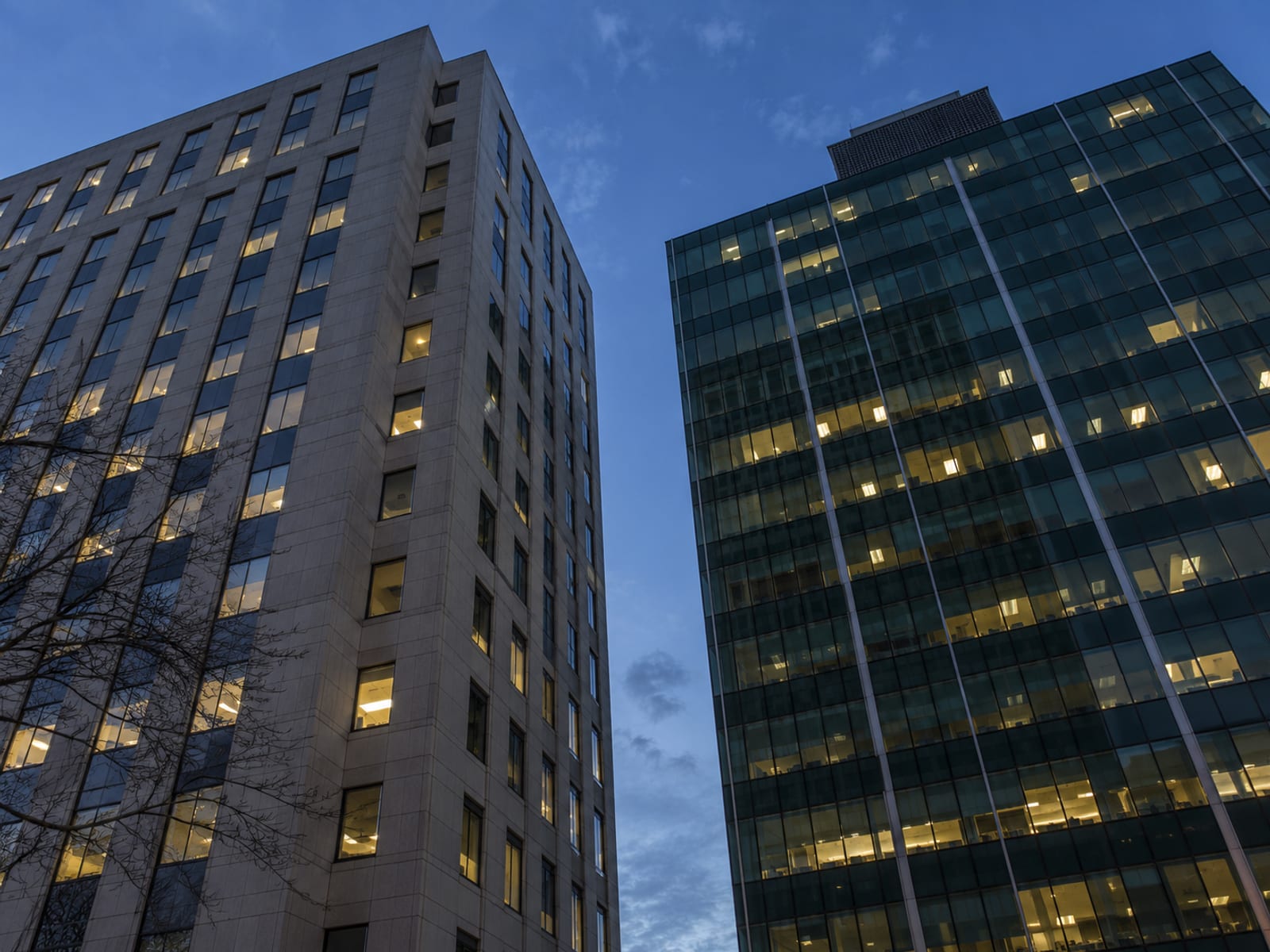 Two glass office towers standing side by side against an evening sky