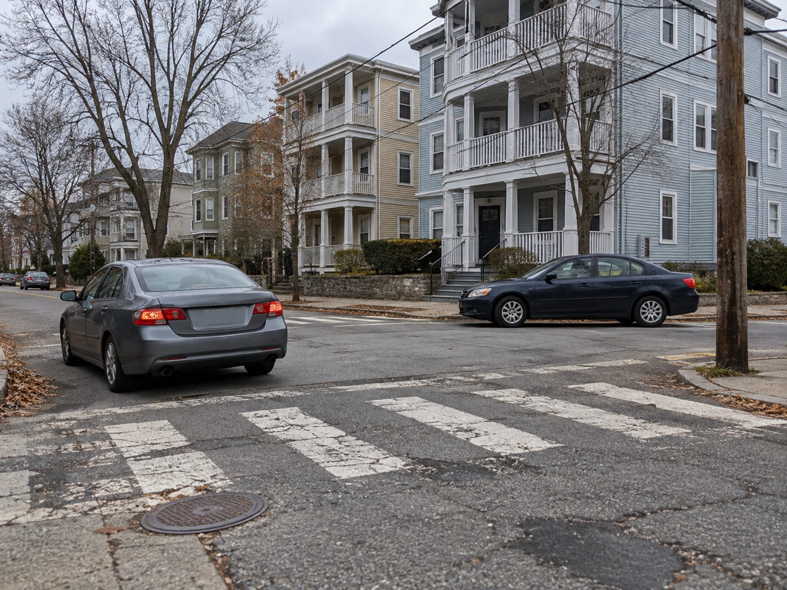 Two parked sedans at a quiet intersection with a crosswalk on a residential street