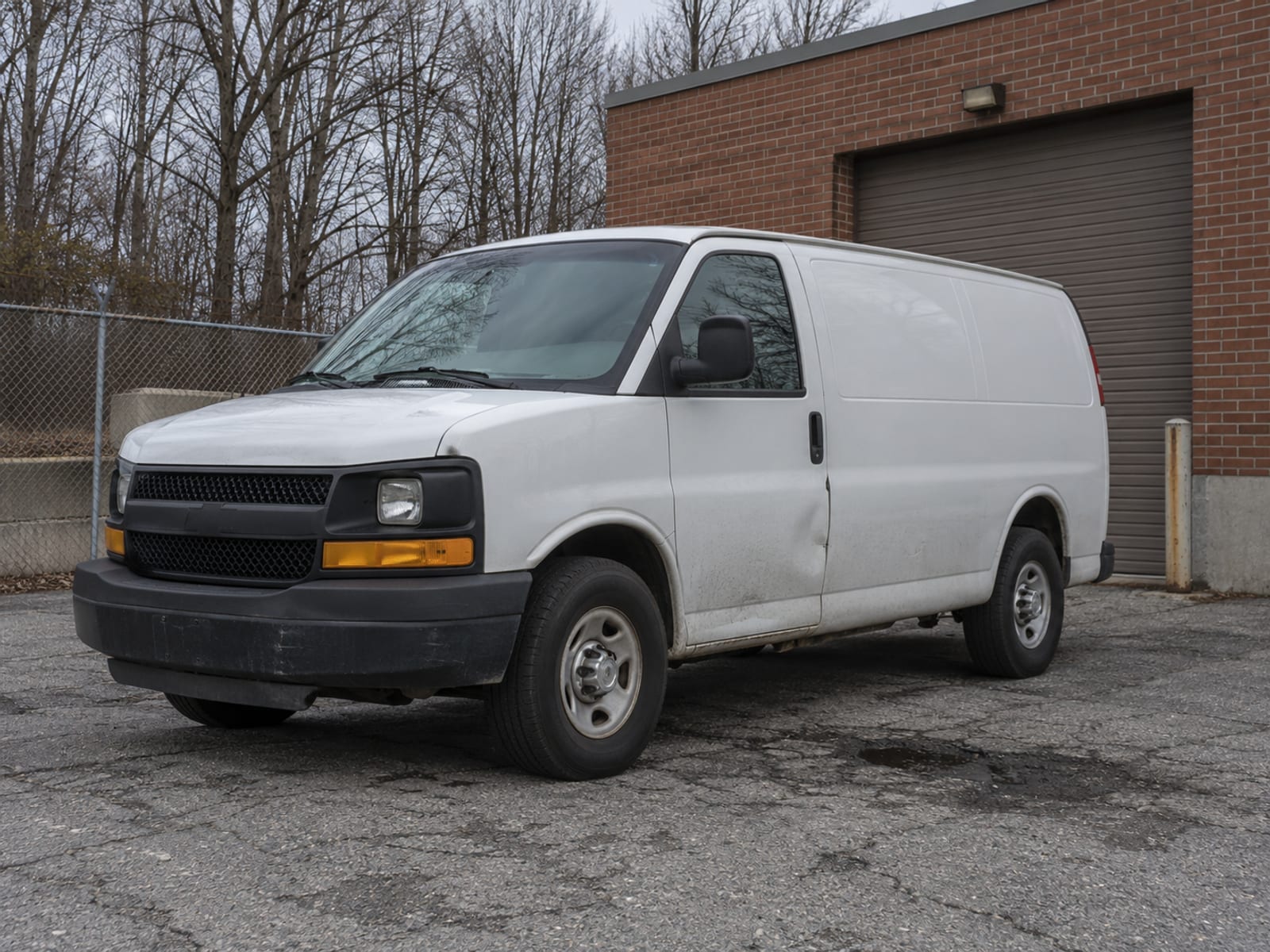 An unmarked white work van parked beside a small commercial building