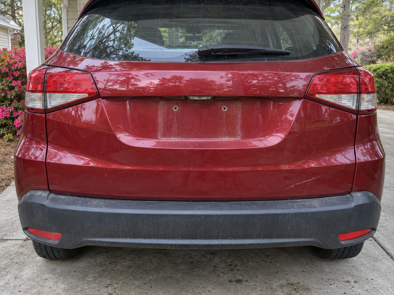 The rear of a parked car in a driveway with an empty license plate bracket