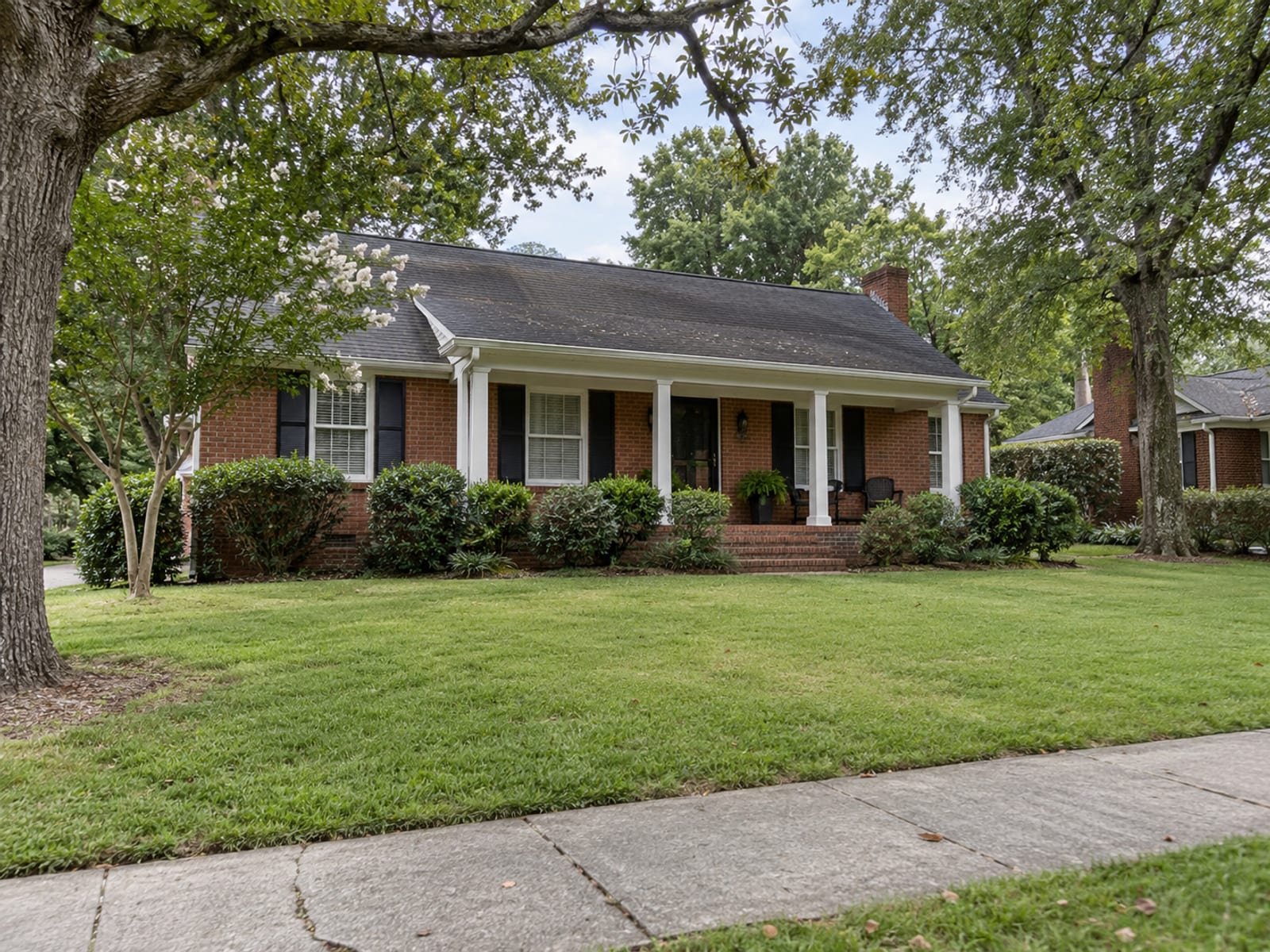 A single-family brick home with a front porch and a neat lawn on a quiet South Carolina street