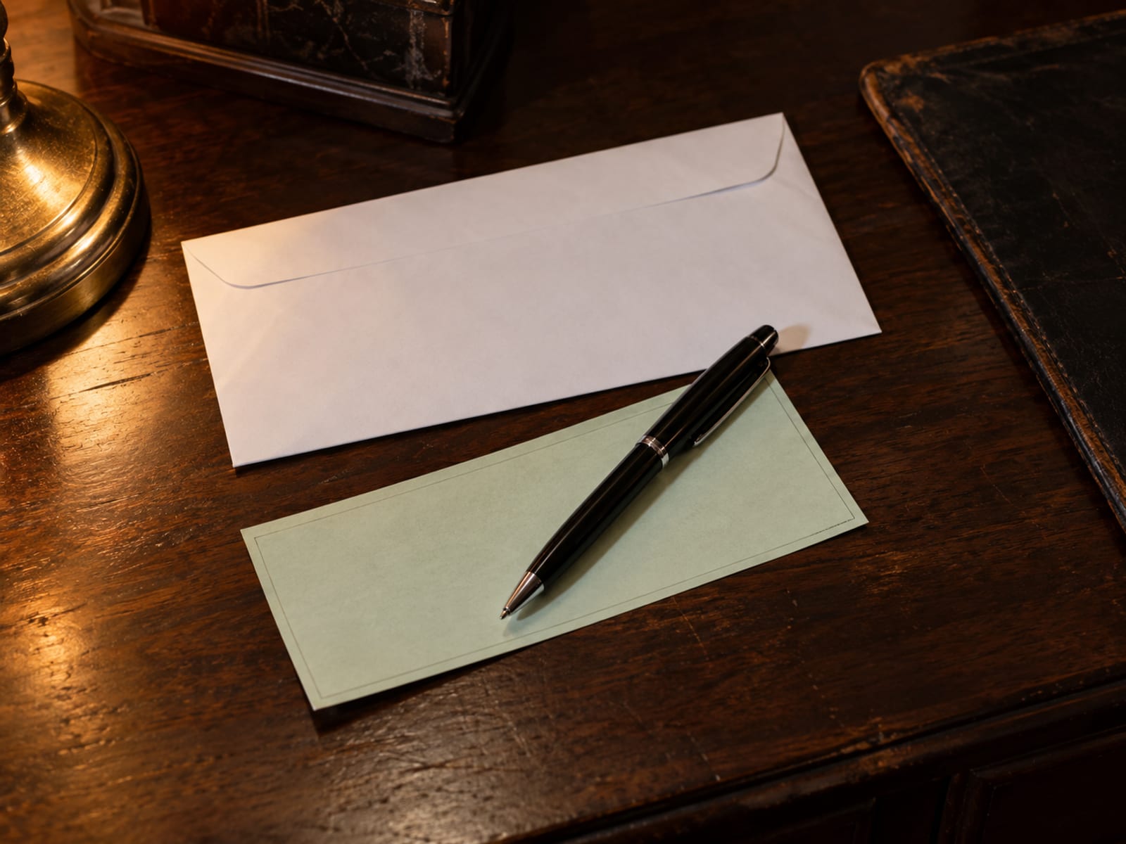 An envelope, a blank check and a pen on a wooden desk