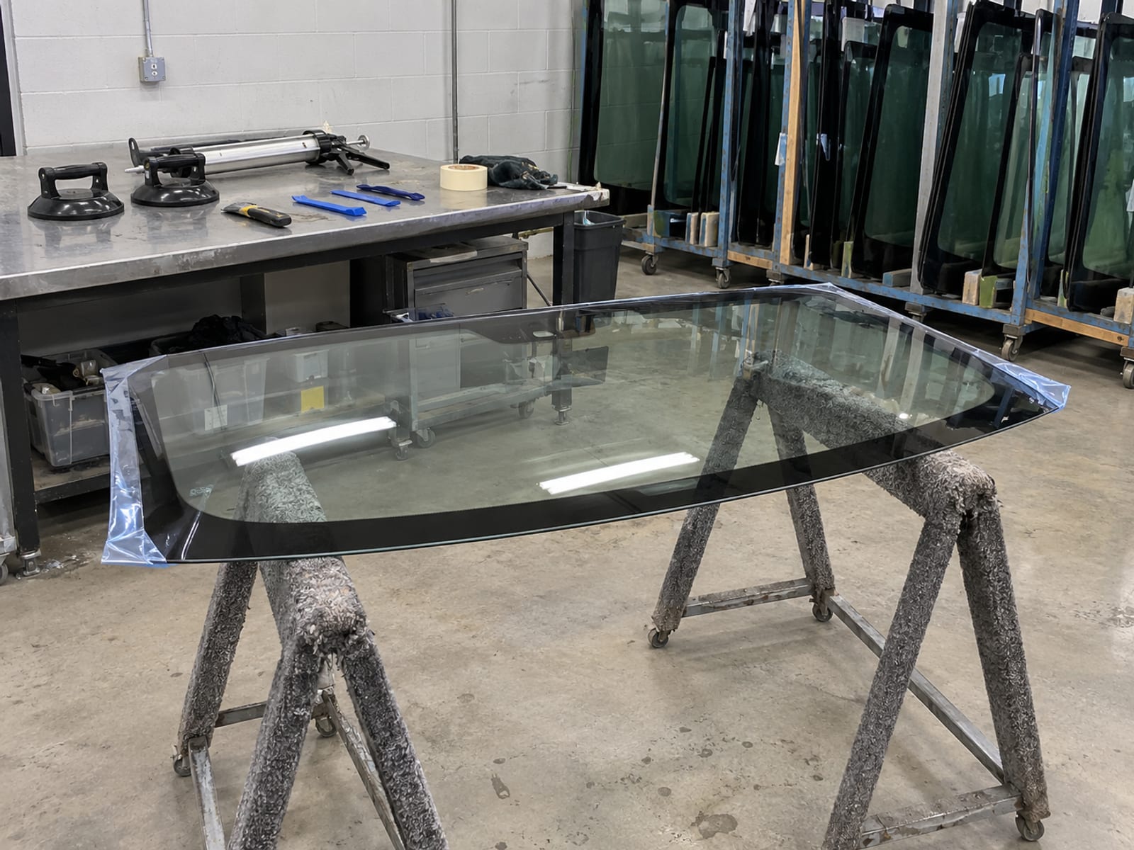 A new windshield resting on padded stands inside an auto glass workshop
