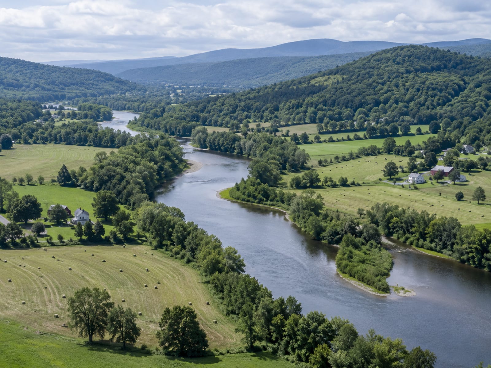 A winding Vermont river running past farm fields and a few houses in a green valley