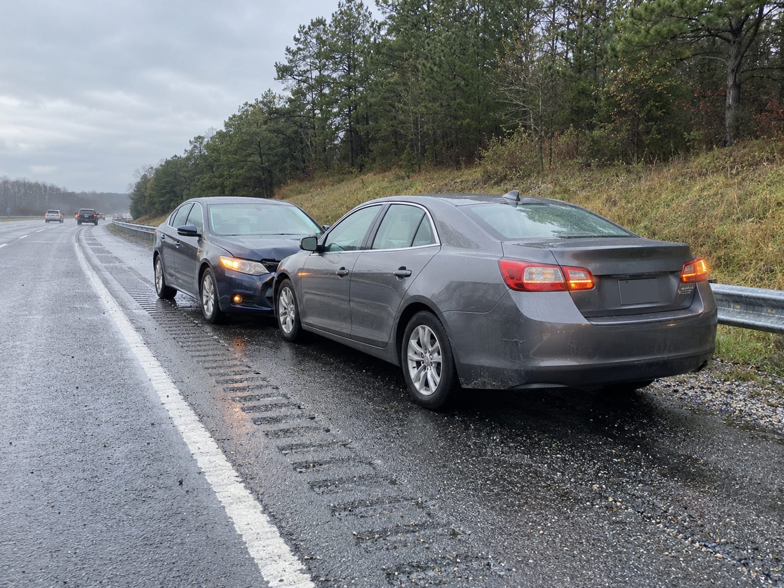 Two cars stopped on a highway shoulder after a minor rear-end collision